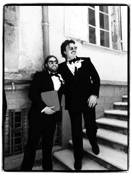 Groomsmen portrait of two groomsmen with bow ties, standing on a stone staircase beside a windowed wall.