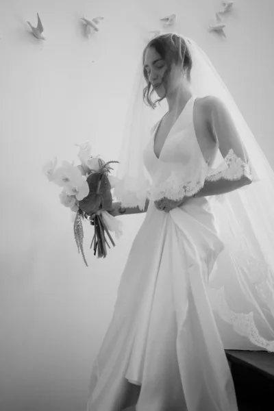Bridal portrait of a bride with veil against a white wall adorned with ceramic birds beside a staircase