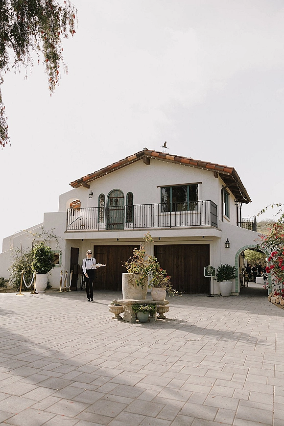Wedding venue exterior with string lights over a Spanish style wedding venue courtyard, arched doorway and stone fountain on pavers