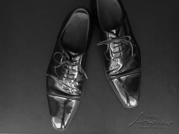 Groom shoes, black oxford shoes with neatly tied laces resting on a leather surface, showcasing polished formal wedding footwear details