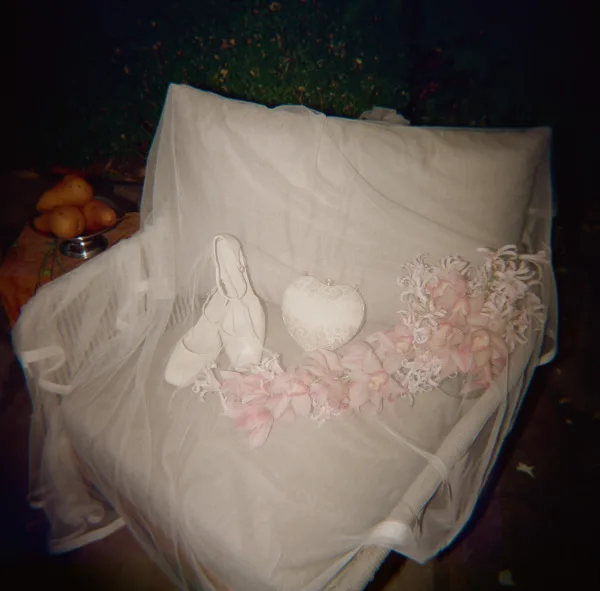Bridal accessories flat lay with wedding shoes flat lay, veil, floral crown and lace heart ornament on a chair amid green foliage
