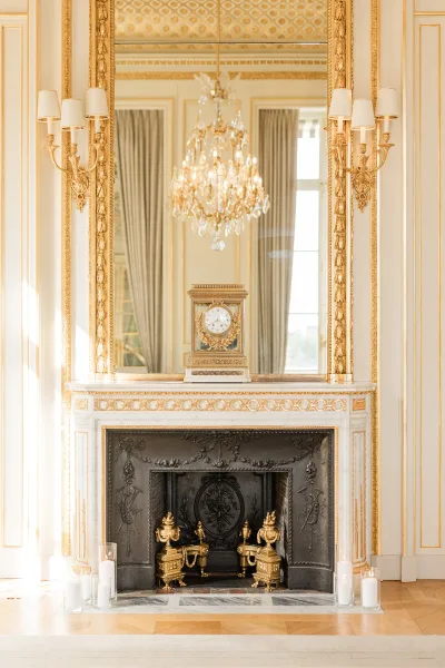 Fireplace mantel decor styled as a romantic fireplace ceremony backdrop, aglow with candles against curtains, windows, and classic wall paneling.