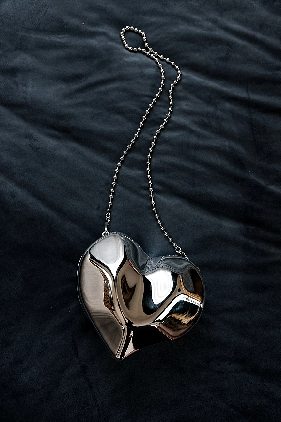 Heart locket necklace with a silver heart locket on a beaded chain, resting on dark fabric for a moody wedding jewelry detail flatlay