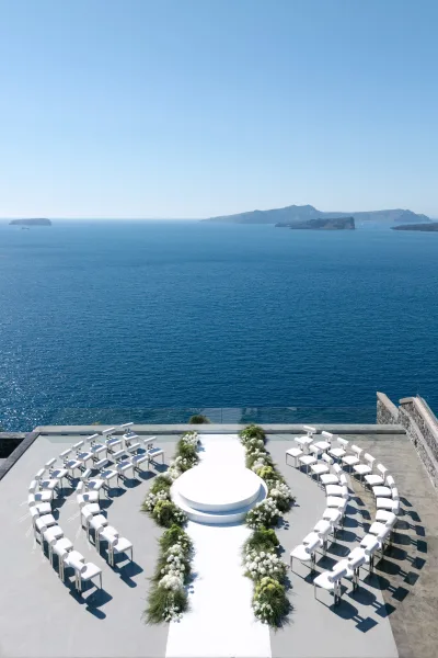 Ceremony setup for an oceanfront ceremony on a round ceremony platform, overlooking a blue ocean and distant islands from a concrete terrace.