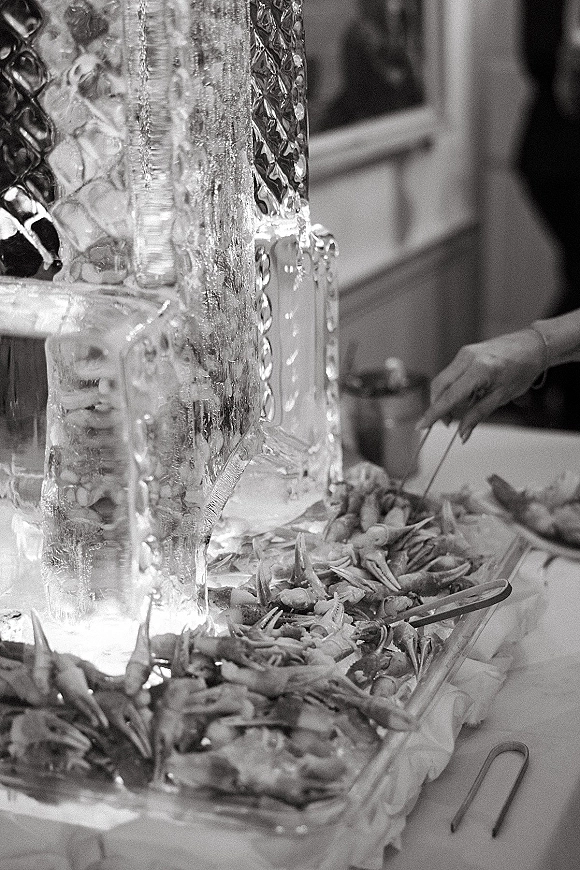 Ice sculpture wedding ice sculpture in progress on a reception table with carving tools, ice chips, and a clear carved ice block indoors