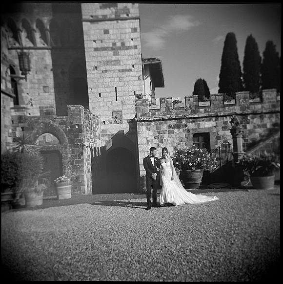 Couple portrait in a black and white wedding portrait, bride in strapless dress and veil with groom in tux at a stone castle doorway