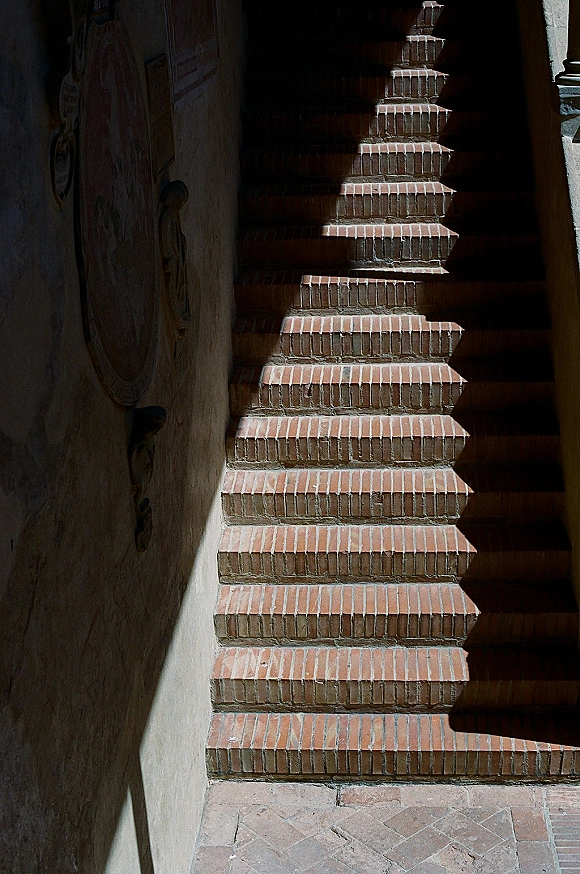 Wedding venue stairs with brick stairway photo details, dramatic shadows on brick steps beside a stone wall and carved wooden door knocker