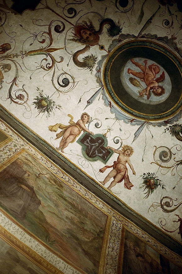 Ornate painted ceiling in a wedding venue ceiling with cherub frescoes, circular medallion, scrollwork, and gold trim on plaster