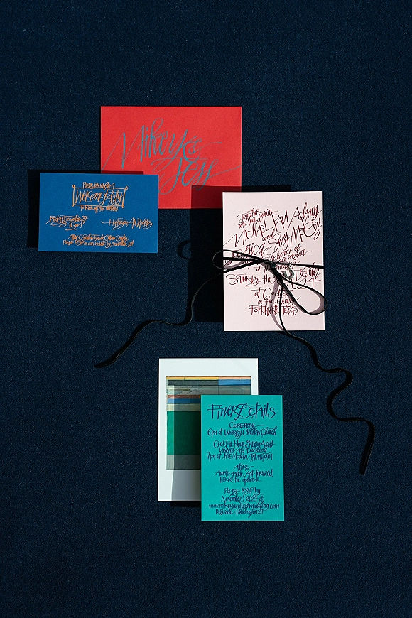 Wedding invitations with modern wedding invitation suite styling, calligraphy cards and RSVP, black ribbon and envelope on navy fabric backdrop
