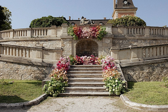 Ceremony aisle design with a flower lined wedding aisle of bright meadow florals along a stone staircase and balustrade at a historic terrace