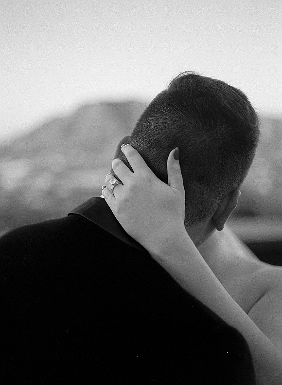Wedding couple portrait in a black and white wedding photo, bride’s hand on groom’s neck showing ring stack, mountains behind