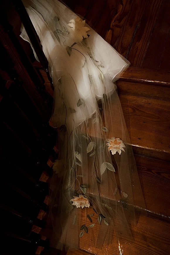 Bridal veil with floral embroidered veil details, sheer embroidered tulle and leaf appliques draped along a wooden staircase railing