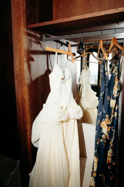 Wedding dress on hanger with strapless bodice and tulle skirt beside a mirror in a wood-paneled room with ocean view