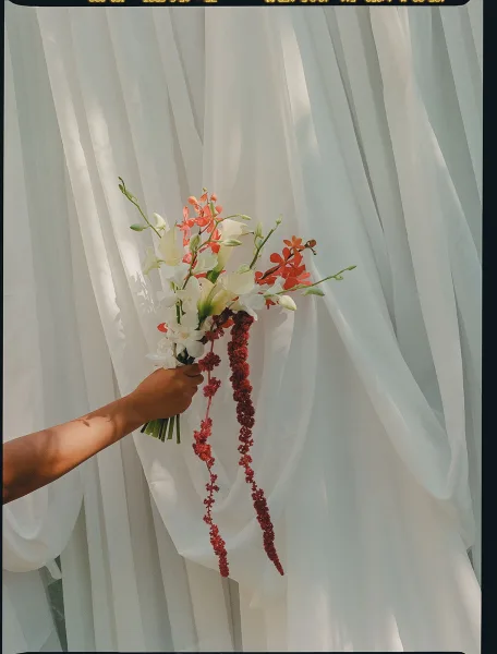 Bridal bouquet in a calla lily wedding bouquet style, sleek white blooms set against a clean white drapery backdrop
