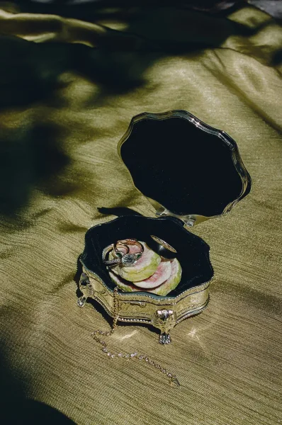 Wedding rings featuring engagement ring detail nestled in a ring box, arranged against green satin fabric for a luxe, polished look.