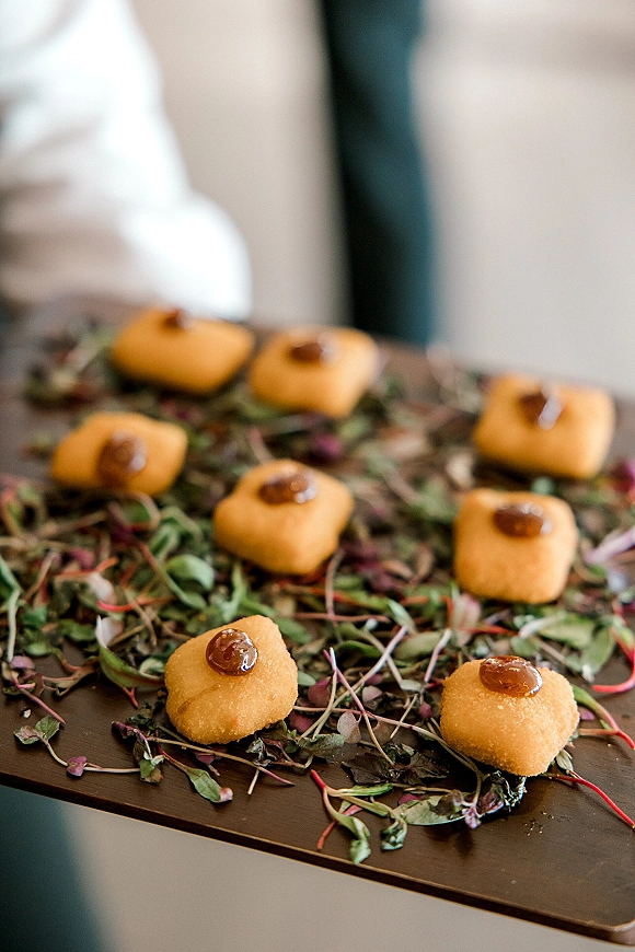 Wedding dessert bites arranged on a wedding dessert platter with bite-size pastries and edible flowers, garnished with greenery indoors