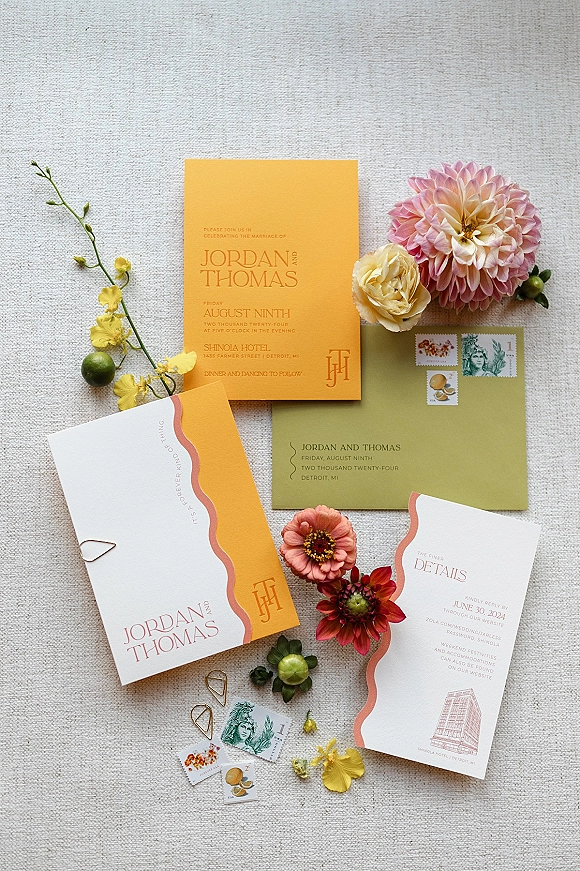 Invitation suite wedding invitation flat lay with envelope, vintage postage stamps, petals and earrings arranged on a linen fabric backdrop