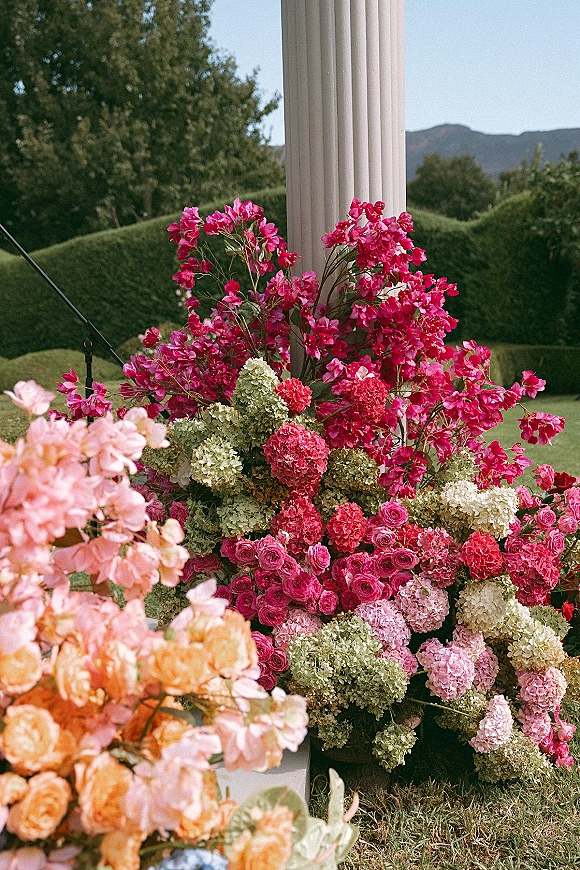 Wedding floral arrangement with ceremony floral arrangements of hydrangeas and roses in buckets by a white column, with mountains behind