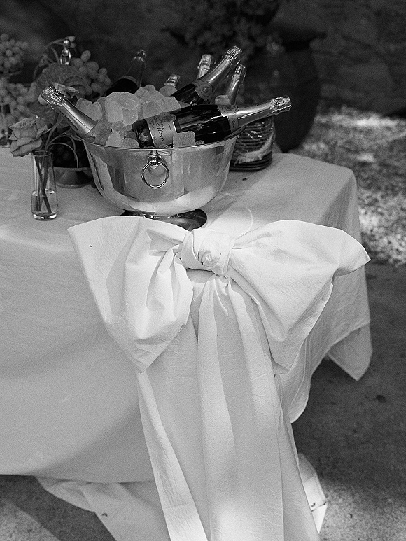 Champagne bucket with champagne on ice, bottles nestled in a metal ice bucket beside a floral vase on an outdoor patio table
