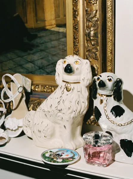 Bridal accessories flatlay with wedding shoes detail, white strappy heels, perfume, bracelet, ring, and ornate gold mirror on a white tabletop