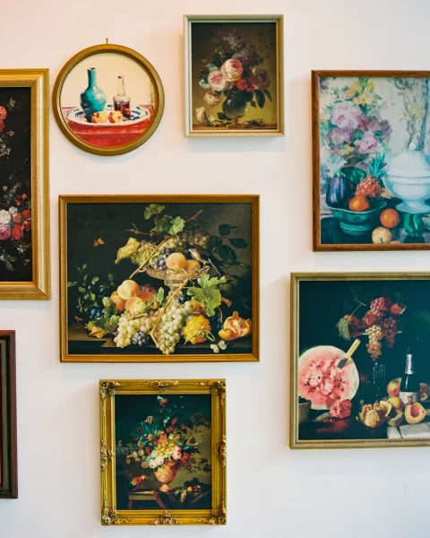 Gallery wall decor with vintage gallery wall of mismatched ornate gold frames holding floral and still life paintings on a white wall