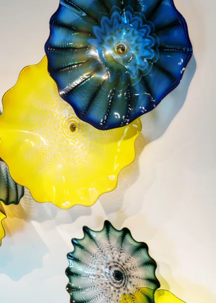 Glass wall art with colorful glass wall sculpture in blue and yellow, arranged as sculptural pieces on a clean white wall display
