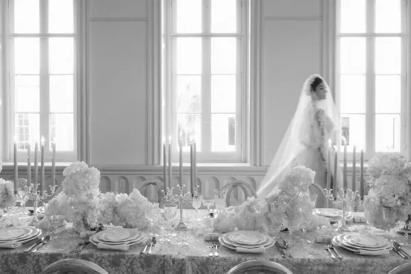 Reception tablescape with white wedding tablescape details, hydrangeas and taper candles on lace cloth, glowing in tall-window natural light