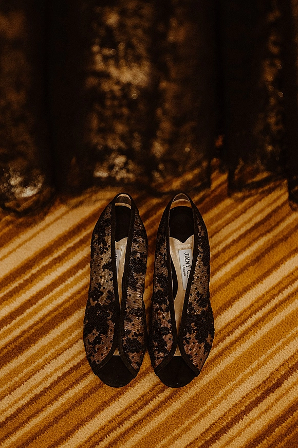 Bridal shoes in black wedding shoes style, pointed-toe lace flats on a striped carpet with soft window-light shadows