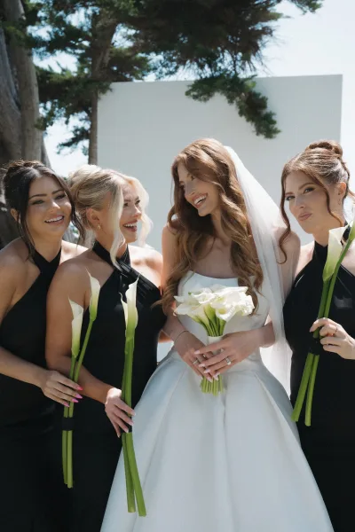 Bridal party portrait of a bride with bridesmaids holding calla lily bouquets, arranged close together in a simple, modern composition.