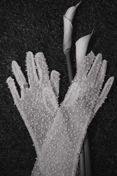 Bridal gloves, delicately pearl beaded, paired with a solitaire engagement ring for an elegant, refined wedding accessory detail.