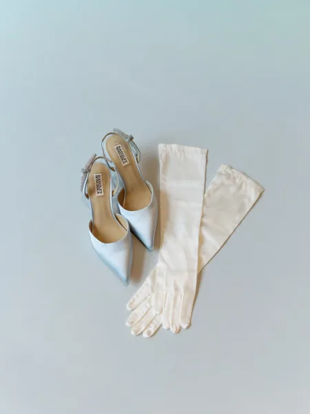 Wedding shoes, blue bridal heels with delicate crystal bows catching light against a pale blue surface