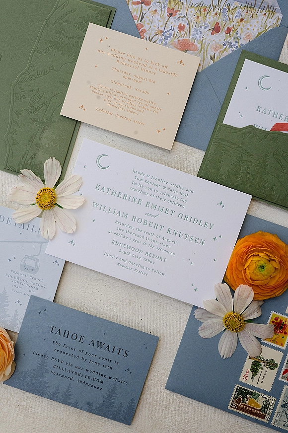 Wedding invitation suite with blue and green wedding invitations, embossed folder, wildflower card, stamps, and daisy accents on linen
