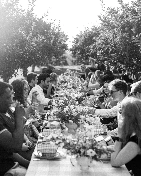 Wedding reception dinner set on a long table wedding reception with wildflower centerpieces and candles in a sunlit orchard garden