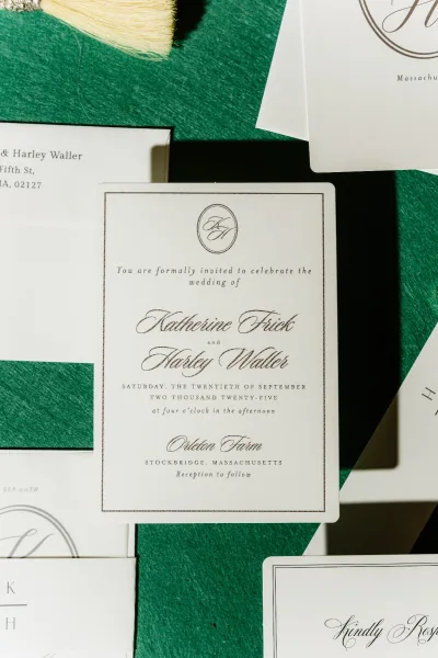 Wedding invitation suite with classic wedding invitations in black ink on deckled paper, gold foil edging and vintage stamps on green fabric