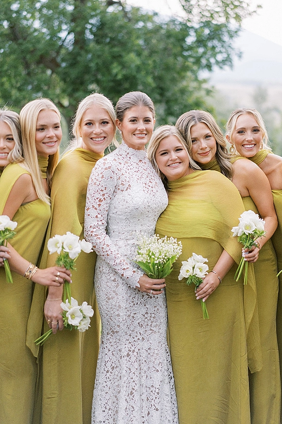Bridesmaids portrait of the bride with bridesmaids, bouquets of white flowers and baby's breath, outdoors with trees and open sky behind