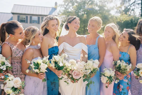 Bride and bridesmaids, the bride laughing with bridesmaids as they hold white and green bouquets in a candid moment