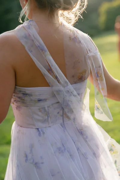 Floral dress detail of a floral tulle dress highlighting a corset bodice, framed by a grass lawn and trees.