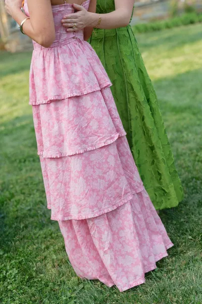 Bridesmaid dresses for mix and match bridesmaids, featuring floral print fabric, posed by a garden stone wall.