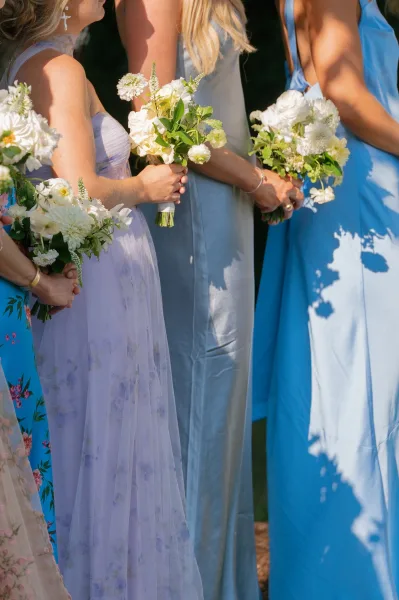 Bridesmaid dresses, mismatched bridesmaid dresses in soft blue and lilac hues, each carrying white florals.