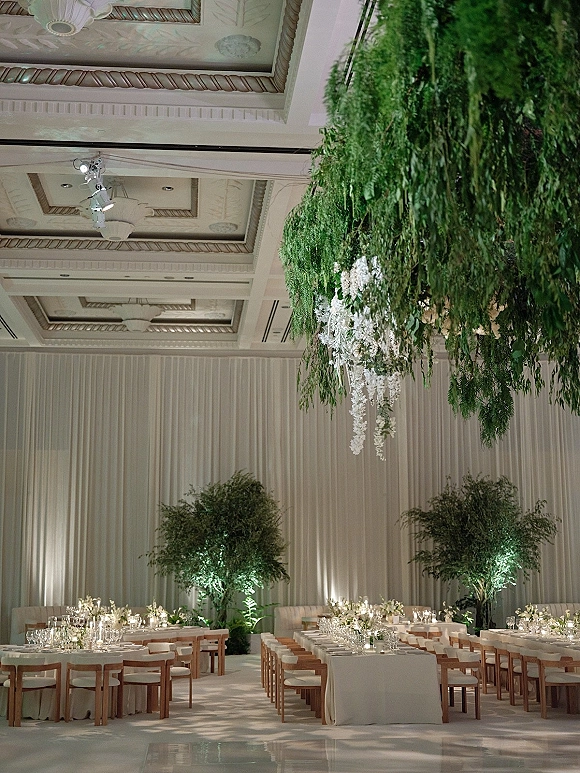 Reception tablescape with a long banquet wedding reception table setup, candlelit runners and florals beneath hanging greenery in a ballroom