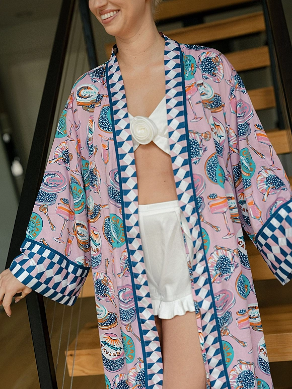Bridal getting ready in a printed bridal robe over a white bralette and shorts, posing on indoor wood stairs by the railing