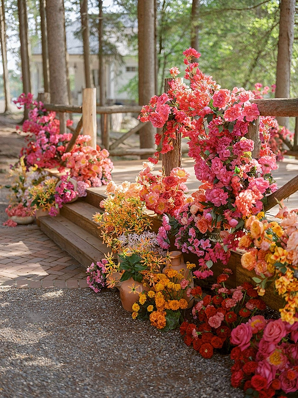 Ceremony aisle flowers in colorful wedding aisle flowers, clustered roses in terracotta vases lining wooden steps with cabin and forest backdrop