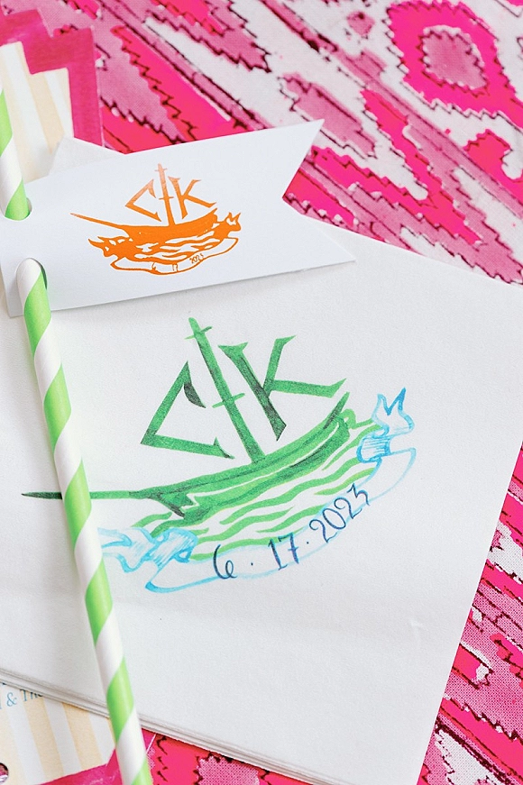 Cocktail napkins with custom cocktail napkins monogram and wedding date beside striped paper straws on a pink patterned tablecloth