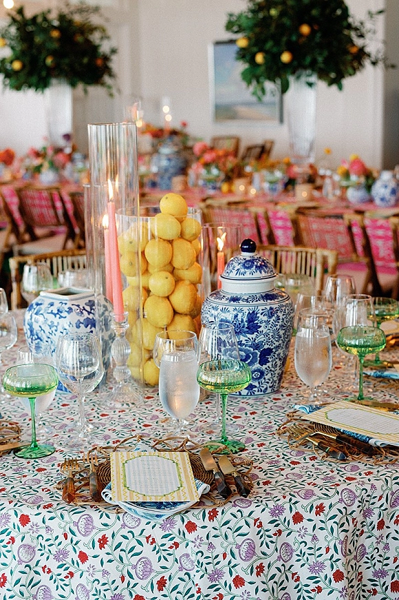Reception tablescape with colorful wedding tablescape details, patterned tablecloth, blue-and-white jars, lemons, taper candles, and floral centerpieces indoors