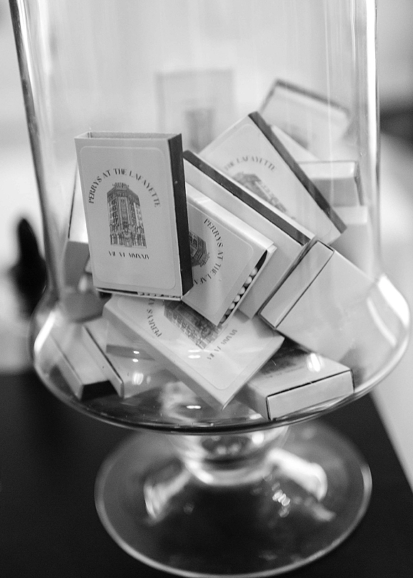 Wedding matchbooks in a glass apothecary jar on a tabletop, custom wedding matchbooks stacked neatly with a blurred indoor background