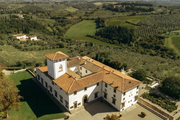 Wedding venue exterior of a villa wedding venue with terracotta roof, stone terrace, and formal hedges overlooking rolling hills and olive groves
