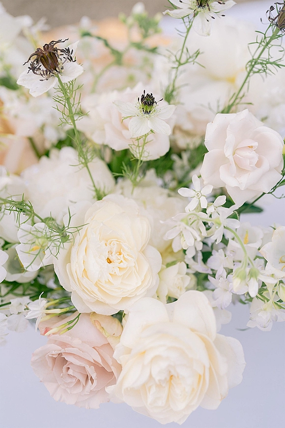 Wedding bouquet with a white rose bouquet of blush and white roses, delicate wildflowers, and greenery arranged on a white surface