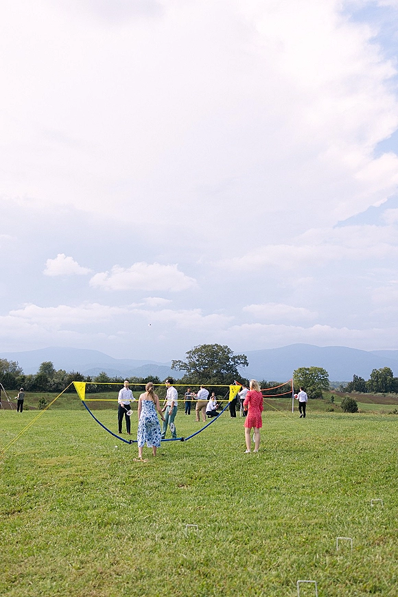 Lawn games set for wedding lawn games with a badminton net, rackets, and shuttlecock on a grassy field with mountains under clouds