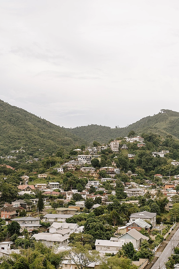 Mountain town landscape with hillside village view, clustered houses and a winding road set against lush green hills and a cloudy sky