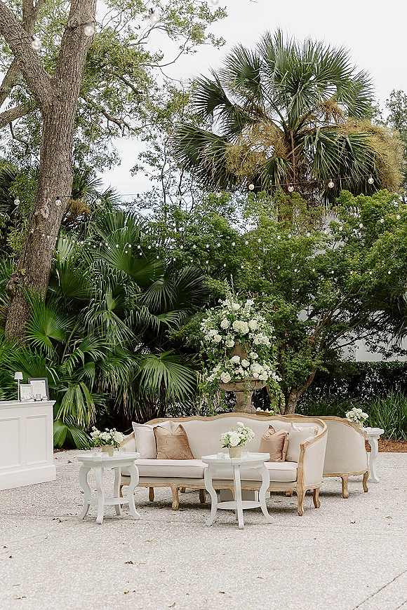 Lounge seating area with vintage sofa and armchair styled for wedding lounge seating, florals and string lights in a palm courtyard